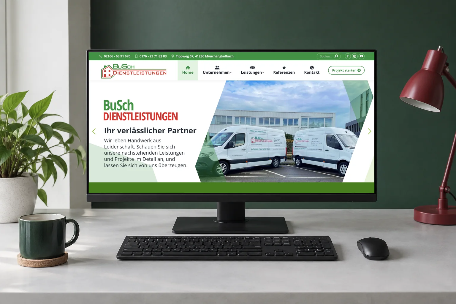 Startseite von BuSch Dienstleistungen mit Firmenfahrzeugen auf einem Desktopmonitor, davor Tastatur und Maus