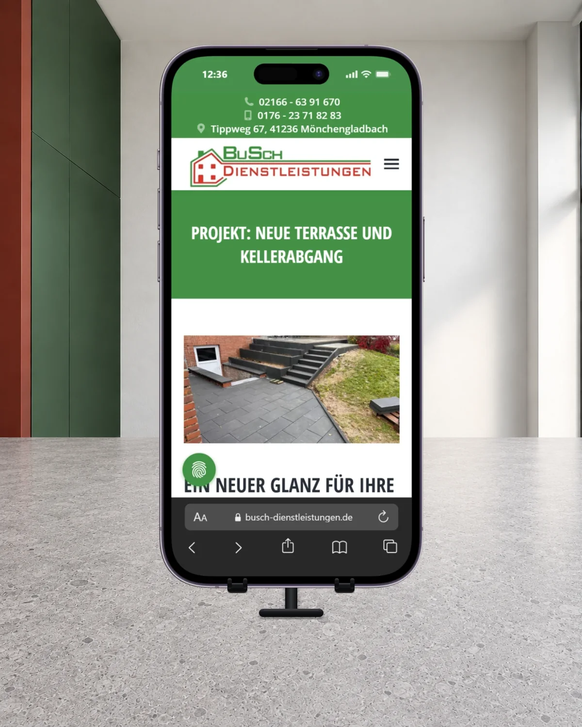 Smartphone mit der BuSch-Projektseite zu einer neuen Terrasse und einem Kellerabgang auf einem Halter