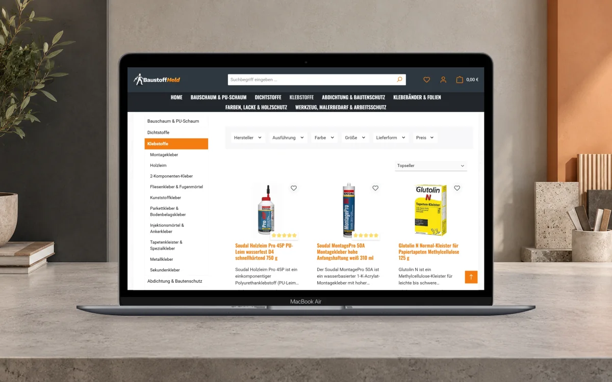 Klebstoff-Kategorie im Baustoff-Held-Shop mit Filtern und Produktübersicht auf einem Notebook.