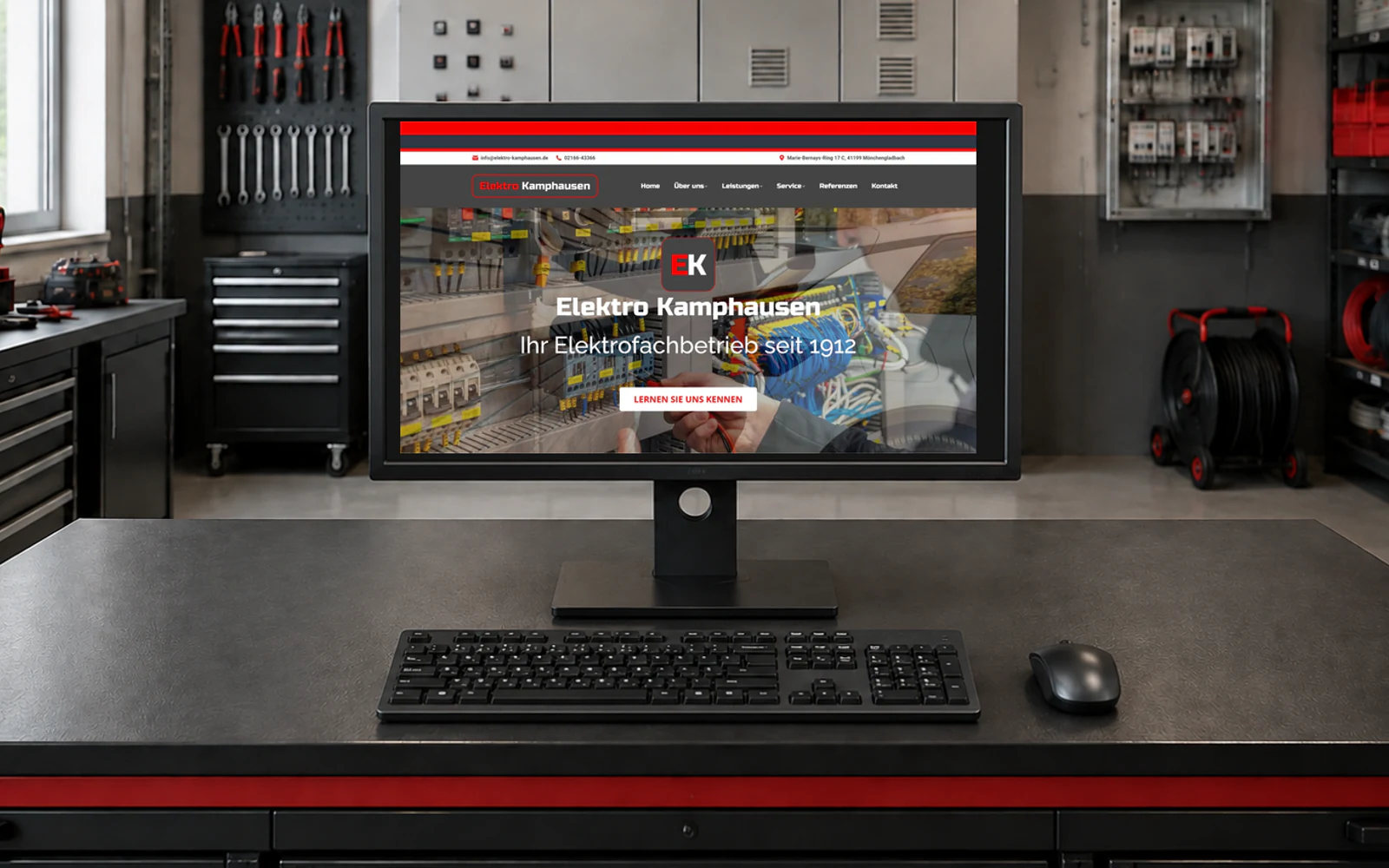 Monitor mit der Kamphausen-Website und Smart-Home-Motiv; davor Tastatur und Maus in einer Elektro-Werkstatt