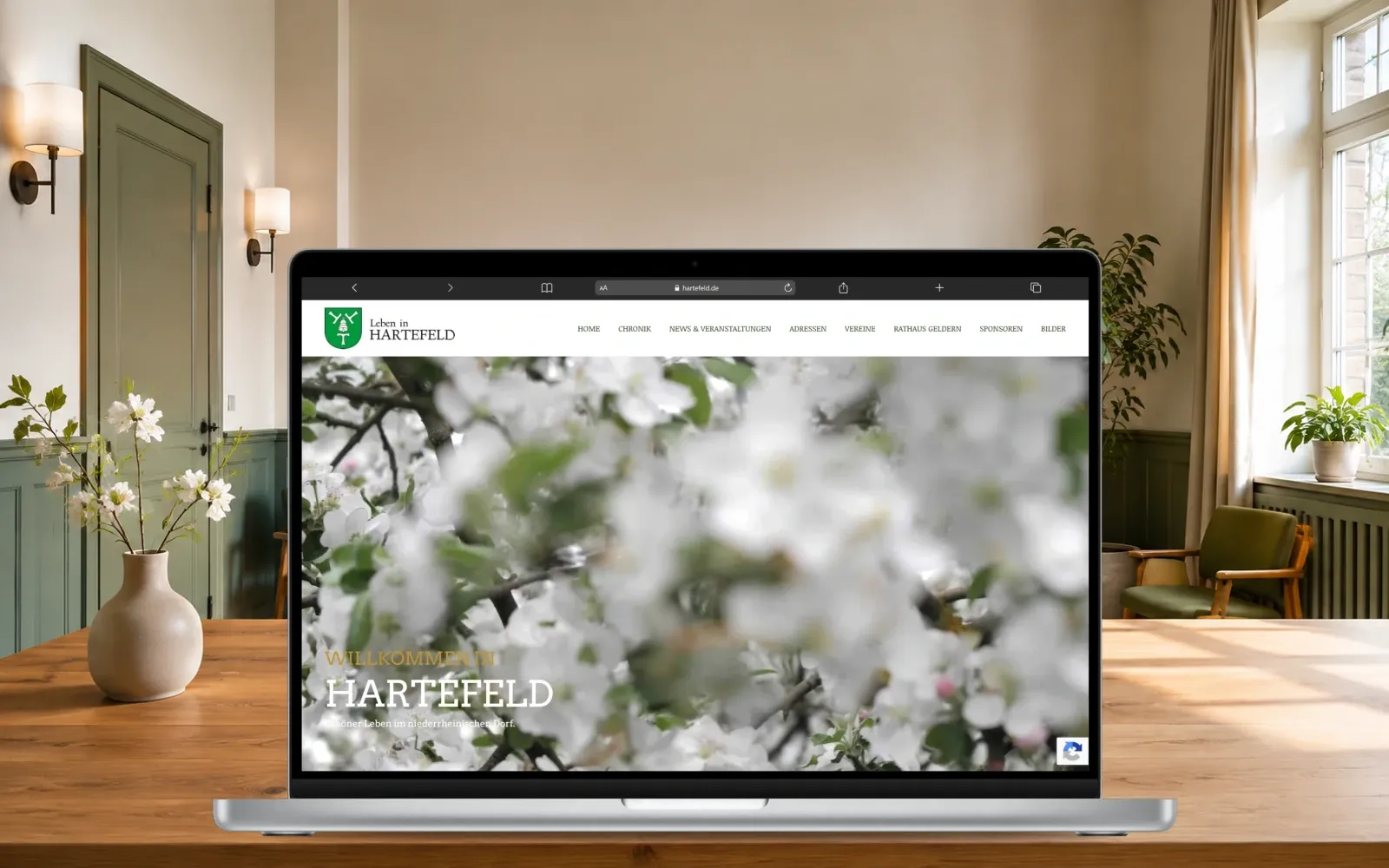 Hartefeld-Website auf einem MacBook in einem freundlich gestalteten Gemeinschaftsraum